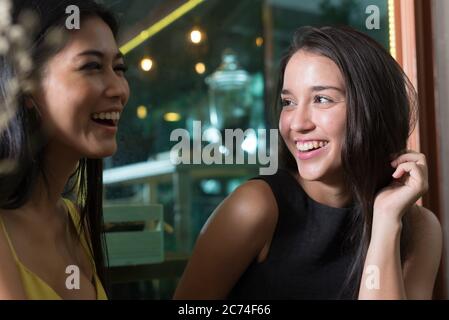 Two happy young beautiful women smiling together at the coffee shop Stock Photo