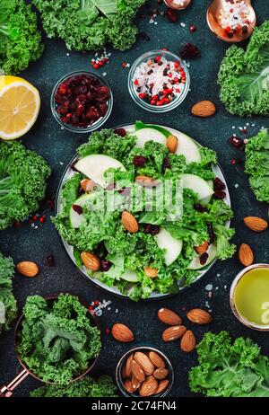 Kale salad with dried cranberry, green apples and almonds. Healthy vegan food, top view, black kitchen table background Stock Photo