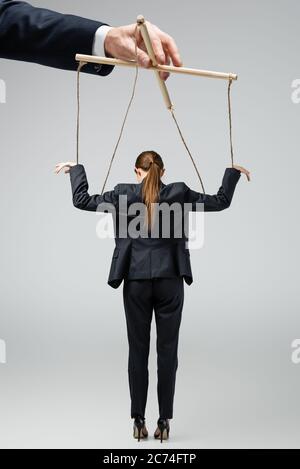 cropped view of puppeteer holding businesswoman marionette on strings  isolated on grey Stock Photo - Alamy