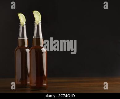 Bottles of dark drink with slice of lime on table and black background Stock Photo