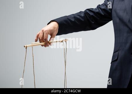 cropped view of puppeteer holding businesswoman marionette on strings  isolated on grey Stock Photo - Alamy