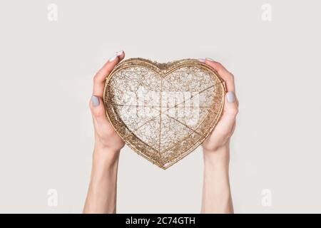 Female hands hold metal wire transparent box in the shape of a heart isolate on white background. Stock Photo