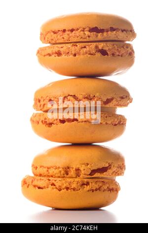 Three orange flavoured macaroons standing on top of each other on white background. Stock Photo