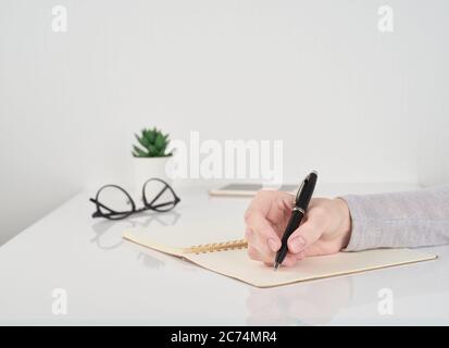 Woman Writing in notebook, Office Work Concept on white wall background Stock Photo