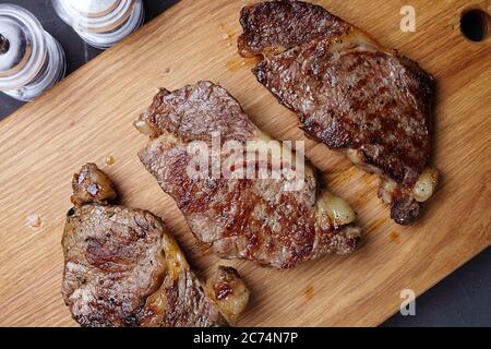 three fried marbled beef steaks on a cutting board, close-up, top view Stock Photo