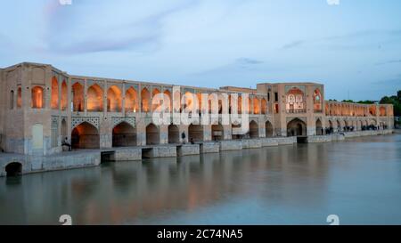 Isfahan, Iran - May 2019: Khaju bridge over Zayandeh river at dusk with lights Stock Photo