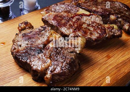three fried marbled beef steaks on a cutting board Stock Photo