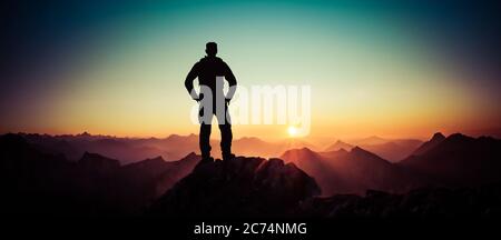 Man reaching summit enjoying freedom and looking towards mountains sunrise. Allgau Alps, Bavaria, Germany and Tyrol Austria. Stock Photo