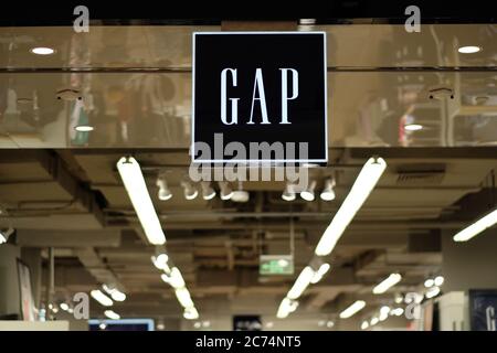 GAP's shop sign hanging in clothing store. Perspective bright white lamps on the ceiling. An American fashion brand Stock Photo