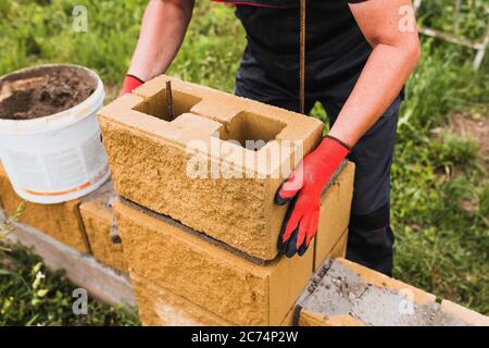 Hard work of a builder - a professional bricklayer skillfully builds walls of brick and concrete block Stock Photo