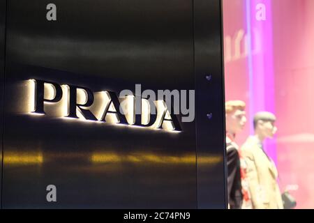 close up PRADA's logo on exterior wall of store at night. An Italian luxury fashion brand. Blur shop window background. Stock Photo