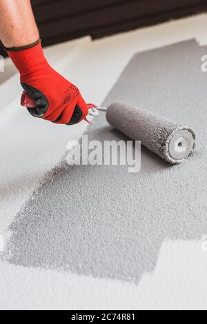 Paint roller paints the white wall in gray - painting works outside the walls with frost-resistant material without harmful chemical impurities Stock Photo
