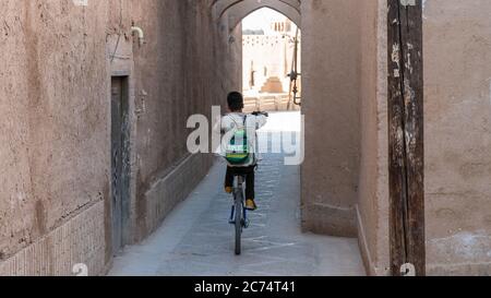 Yazd, Iran - May 2019: Kid on a bicycle riding in the narrow street of old city Yazd Stock Photo