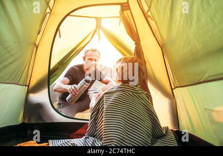 Family lisure concept image. Father and son prepare for camping in mountain, drink tea in tent Stock Photo