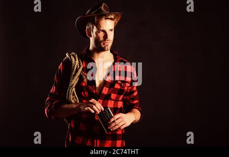 ride a fast horse. cowboy with lasso rope. Western. man checkered shirt on ranch. western cowboy portrait. Vintage style man. Wild West retro cowboy. wild west rodeo. man in hat black background. Stock Photo