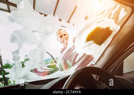 Man washes car front windows with soap foam Stock Photo