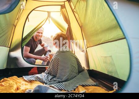 Family lisure concept image. Father and son prepare for camping in mountain, drink tea in tent Stock Photo