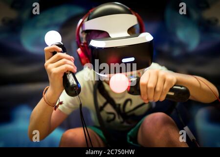 Young teenager boy using a Virtual reality headset with goggles and hands motion controllers in playing game zone. Modern technologies concept image. Stock Photo