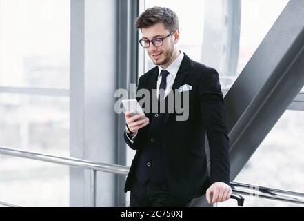 Happy business man texting on smart phone in airport Stock Photo