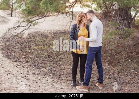 Young happy couple awaiting baby on their walk in the park Stock Photo