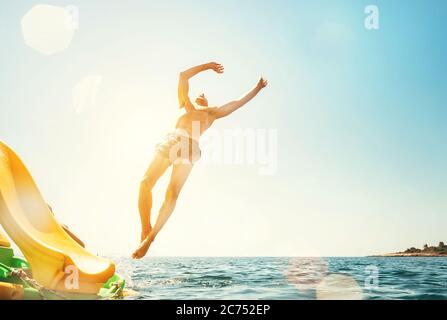 Man jumping backwards somersault into the sea. Happy beach vacation concept image. Stock Photo