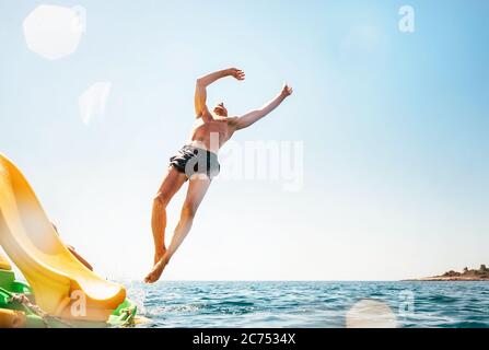 Man jumping backwards somersault into the sea. Happy beach vacation concept image. Stock Photo