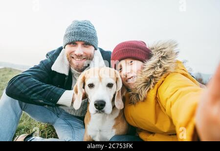 Father and son dressed in warm clothes taking a selfie photo with their best family member beagle dog Stock Photo