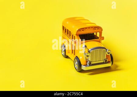 Simply design yellow classic toy car school bus isolated on yellow colorful background. Safety daily transport for kids. Back to school concept. Education symbol. Copy space Stock Photo