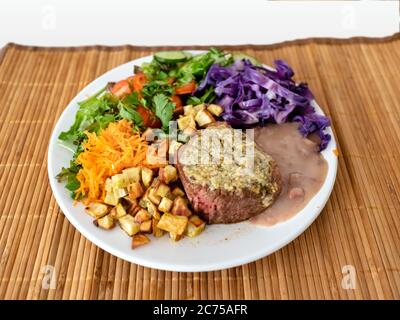 White crockery dish, with green salad, tomato, red cabbage, carrot, sweet potato, beans and meat, on straw base, Rio de Janeiro, Brazil Stock Photo