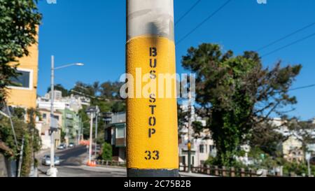 Bus stop sign on a pole with blurred background in San Francisco, California, USA Stock Photo