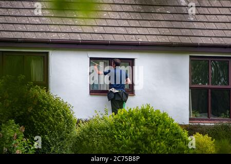 A window cleaner cleaning windows on a house, Chipping, Preston, Lancashire. UK. Stock Photo