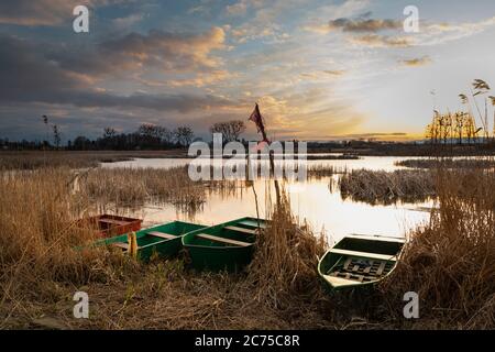 Fishing boats on the lake shore and cloudy evening sky Stock Photo