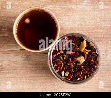 Glass with leaf of karkade tea and brewed tea in disposable paper cup on wooden rustic background. Stock Photo