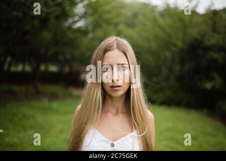 Portrait of beautiful blonde woman with bouquet of blue flowers. Young woman walking alone in the summer park after covid-19 coronavirus pandemic Stock Photo