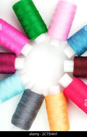 Sewing threads of different colors on reels on a white background in a circle. Stock Photo