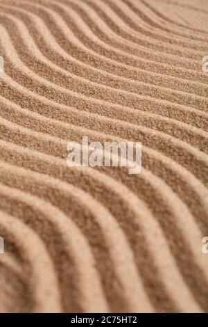 Wavy pattern on a beach in the summer. The textured surface of sand on the beach after a strong wind in the form of waves close up. Stock Photo