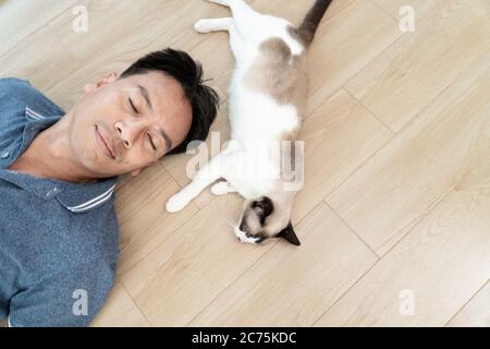 Asian man with elder cat lying on floor at home Stock Photo