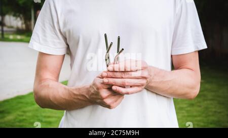 Man in white t-shirt holding a reusable steel drinking straw. Eco lifestyle and zero waste concept. Plastic free Stock Photo