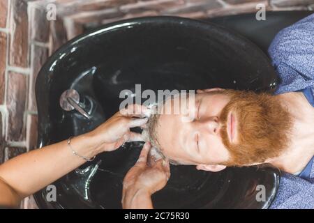Barber woman washes customer man head. Concept barbershop.