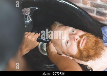Barber woman washes customer man head. Concept barbershop. Stock Photo
