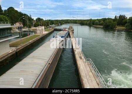 Evry, France. July 04. 2020. Dam on the river Seine south of Paris. Barge in a lock that fills with water to pass the drop. Stock Photo