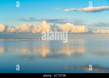 Golden early morning clouds reflect in the still waters of Summerside Harbour, Prince Edward Island, Canada. Indian Point lighthouse on the horizon. Stock Photo