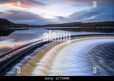 The overflow at Fewston Reservoir in full force as the water cascades down to Swinsty below, with cloud motion captured in the sky above. Stock Photo