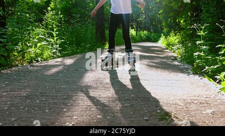 A little girl learning how to skate on her rollers in the park. Mid shot Stock Photo