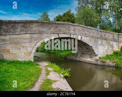 Sandstone Bridge 23 on a quiet, rural section of the Leeds to Liverpool Canal in Lancashire, UK. Taken on a sunny day with blue sky Stock Photo