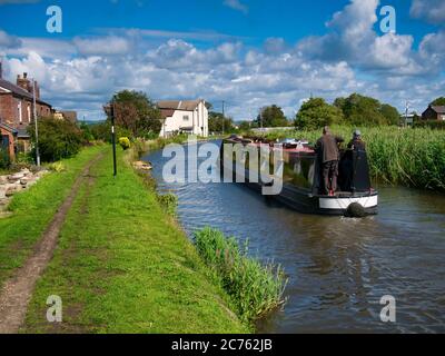 Holidaymakers on a narrowboat cruising on the Leeds to Liverpool Canal in tranquil, rural Lancashire. Taken on a sunny day in summer. Stock Photo