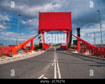 The counterweight and hydraulic rams of a red bascule bridge carrying road and pedestrian traffic across part of the docks complex in Birkenhead, UK. Stock Photo