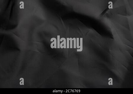 Black wrinkled material with wrinkles and contrasting texture. Dusty packaging. Abstract dramatic background. For design and headlines. Copyspace Stock Photo