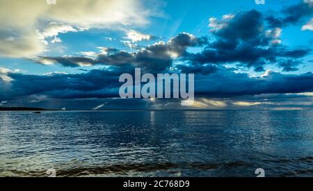 The sea after a storm over the Swedish Baltic Sea at sunset where the sun's rays light up between the clouds and the sky starts to turn blue again lat Stock Photo