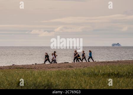 A fitness class in progress, group practicing exercises on the beach. Stock Photo